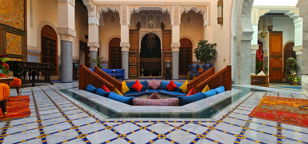 Colorful seating area in a riad with charming Moroccan zellige tilework and a pool.