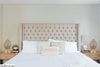 Luxurious-white-bed-with-a-tufted-headboard-flanked-by-nightstands-and-cozy-candle-lamps-on-either-side