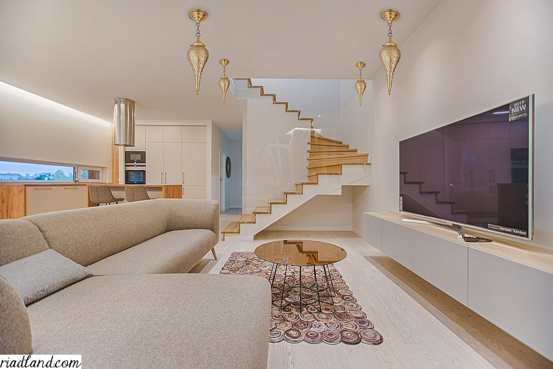 Luxurious-modern-living-room-with-a-staircase-large-beige-couch-and-four-golden-hanging-lamps