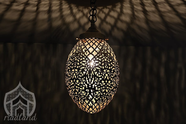 Handcrafted golden brass lamp casting captivating patterns in the darkness, showcasing its unique craftsmanship