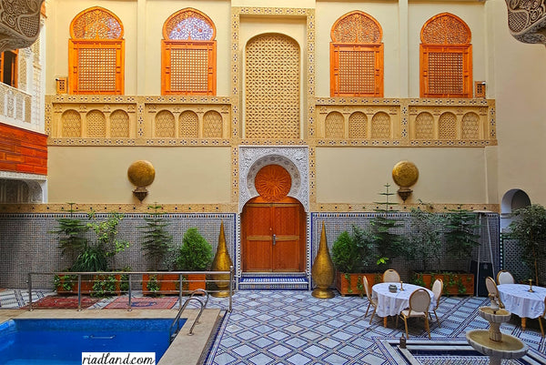 Colorful Riad courtyard featuring two large standing lamps, a fountain, and a swimming pool