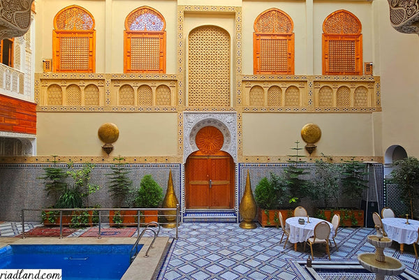 Colorful Riad courtyard featuring two large standing lamps, a fountain, and a swimming pool