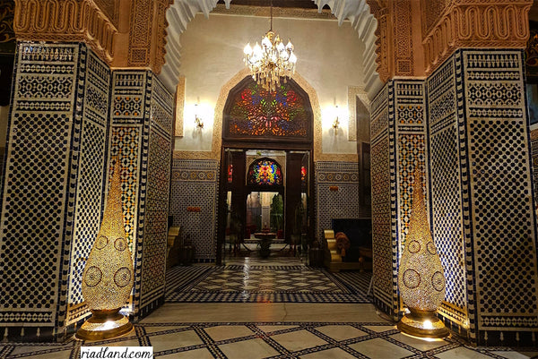 room entrance of a riad with zellige tiles and two big floor lamps on each side 