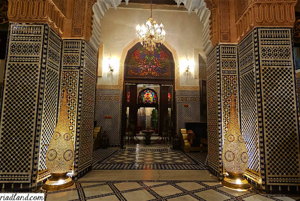 room entrance of a riad with zellige tiles and two big floor lamps on each side 