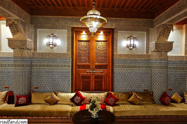 Interior of a riad featuring a traditional Moroccan sofa with authentic pillows and lamps